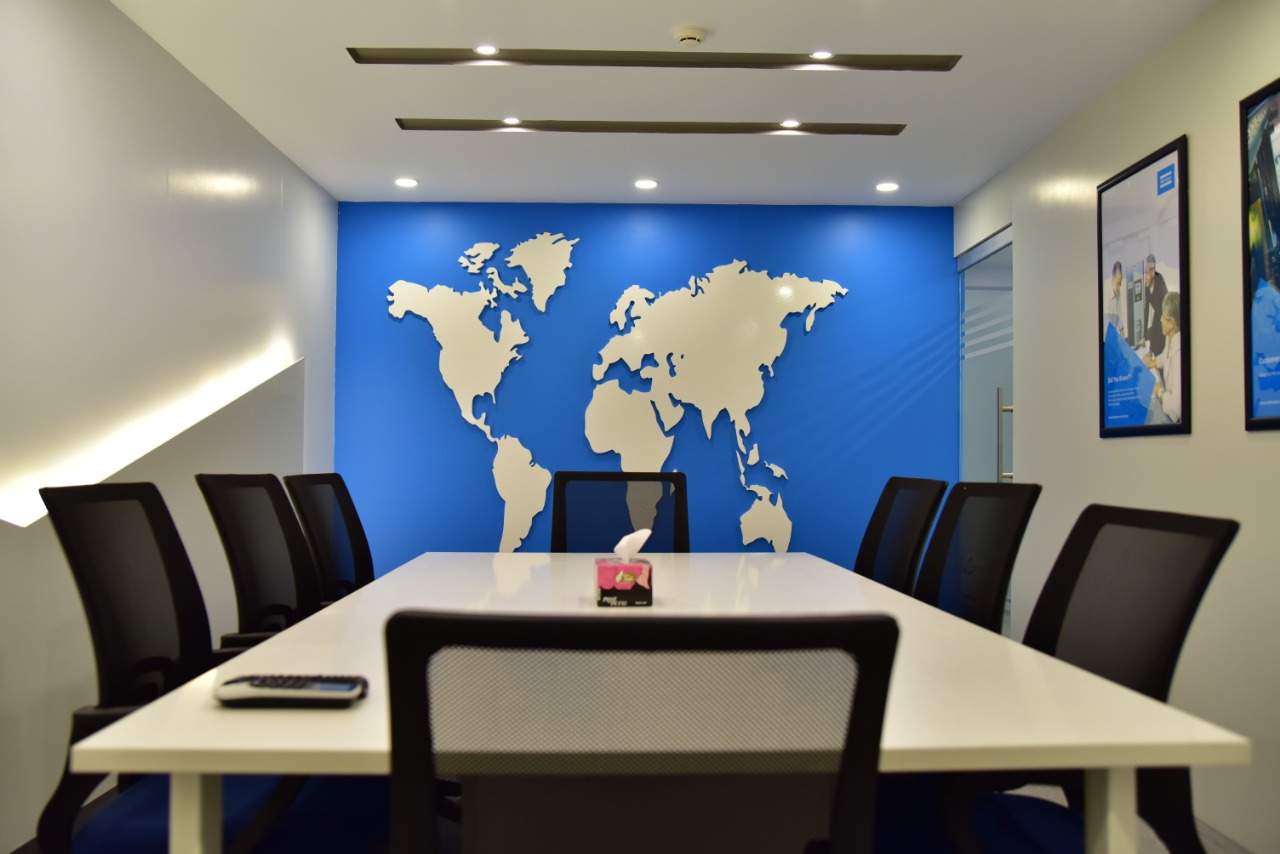Boardroom anchored by a sculpted metal world map on a brand-blue wall