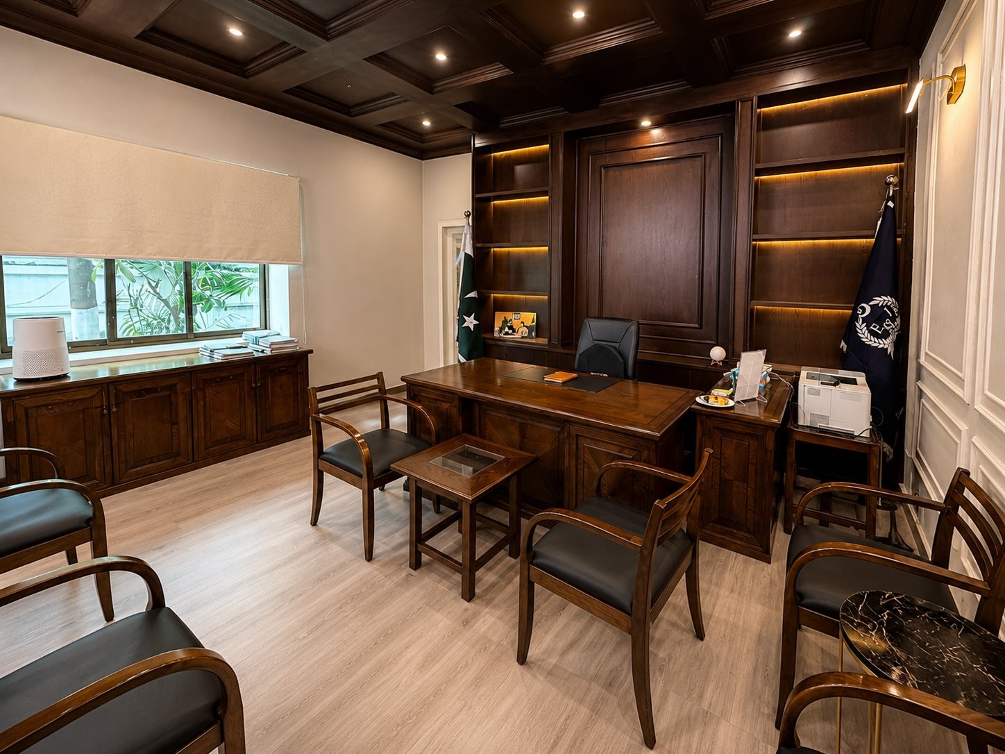 Administrator's office with a wood desk, backlit timber shelving and national flags