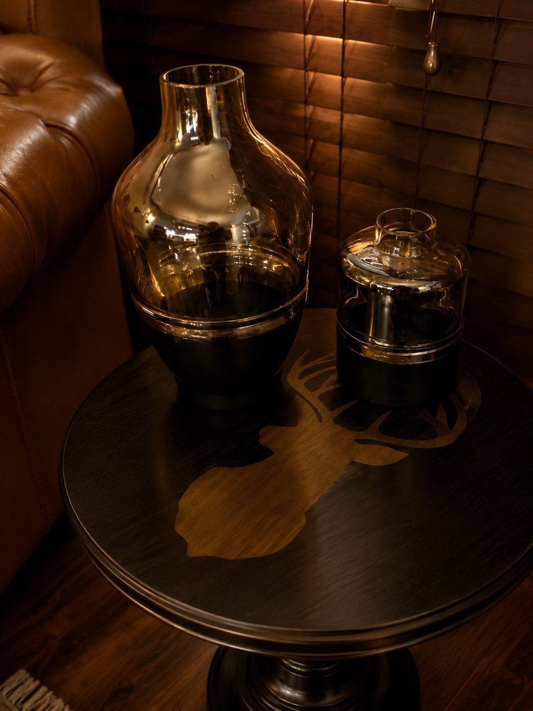 Glass and brass decanters on round side table with deer motif