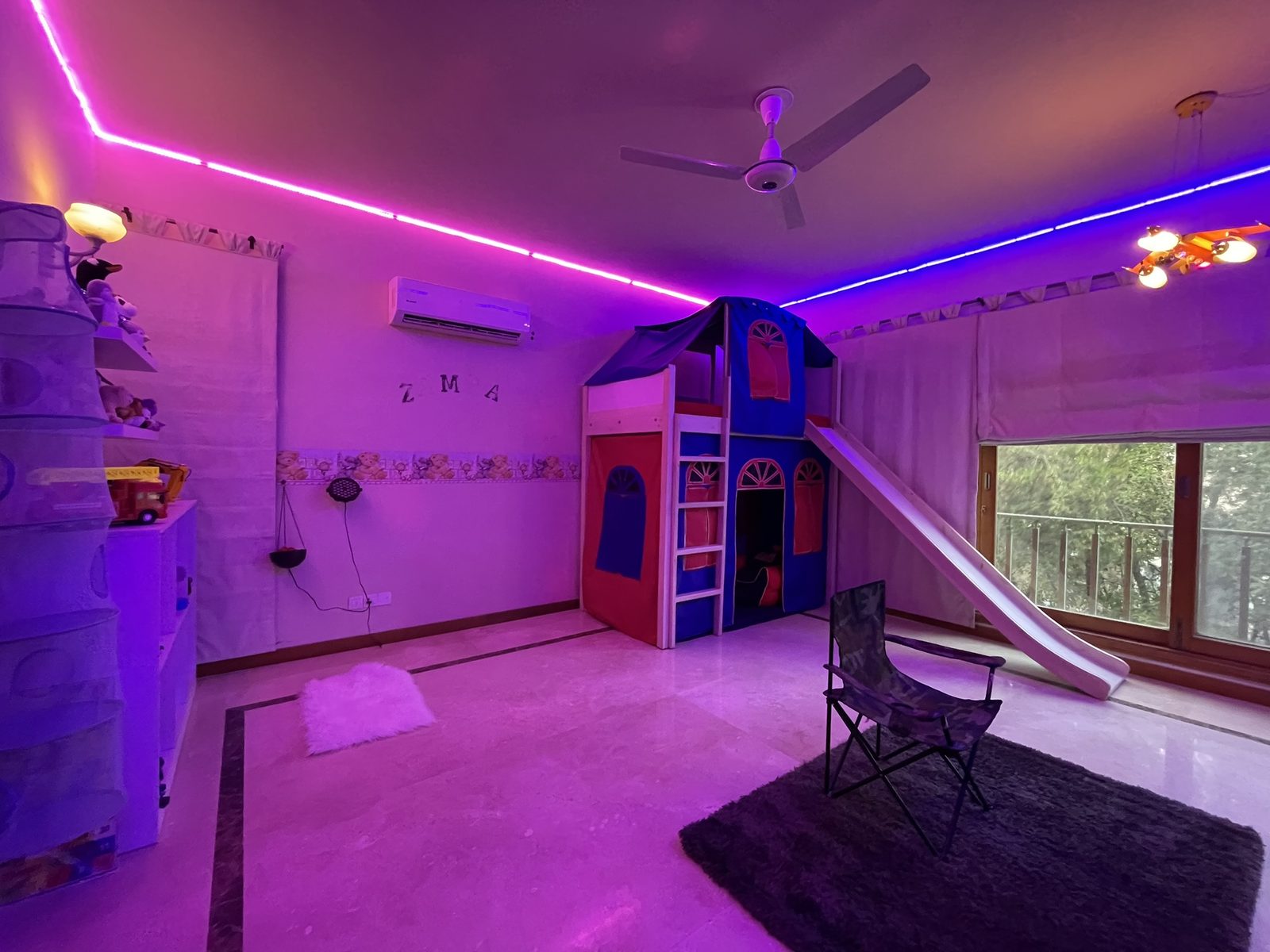 Pink and blue LED-lit playroom with playhouse bunk and slide